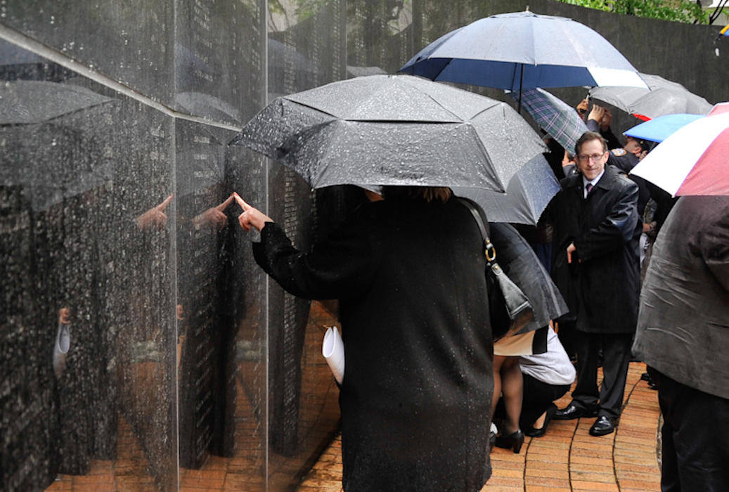 A woman touches a name engraved in the black granite of the New York State Police Officers' Memorial, located at the Empire State Plaza in Albany.
